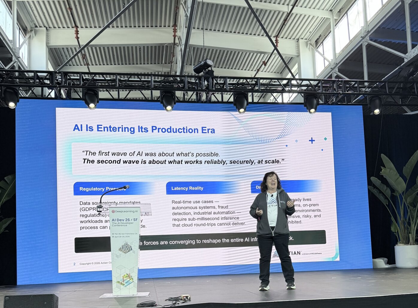 Emma McGrattan, CTO of Actian, on stage with a slide titled 'AI Is Entering Its Production Era' covering regulatory pressure, latency reality, and data residency