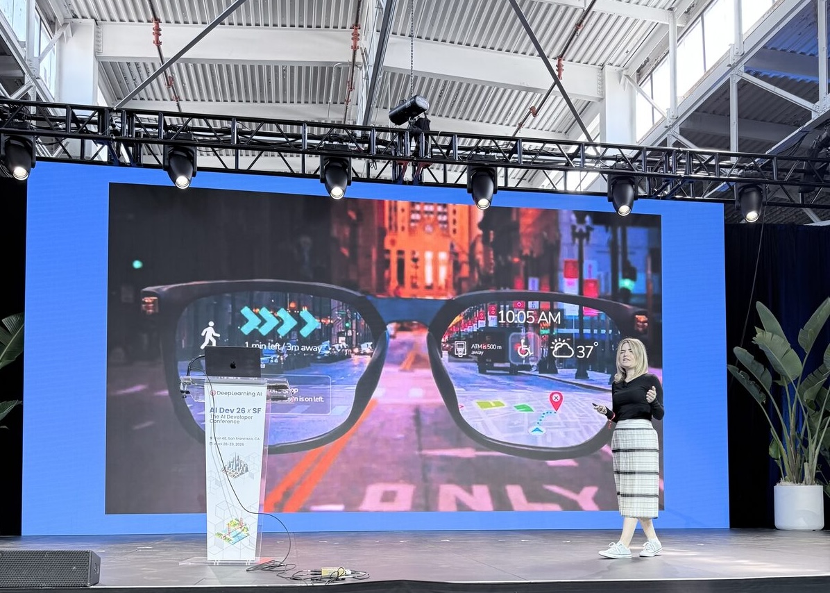 Paige Bailey on stage with a slide showing AR glasses overlaying navigation and weather info on a city street