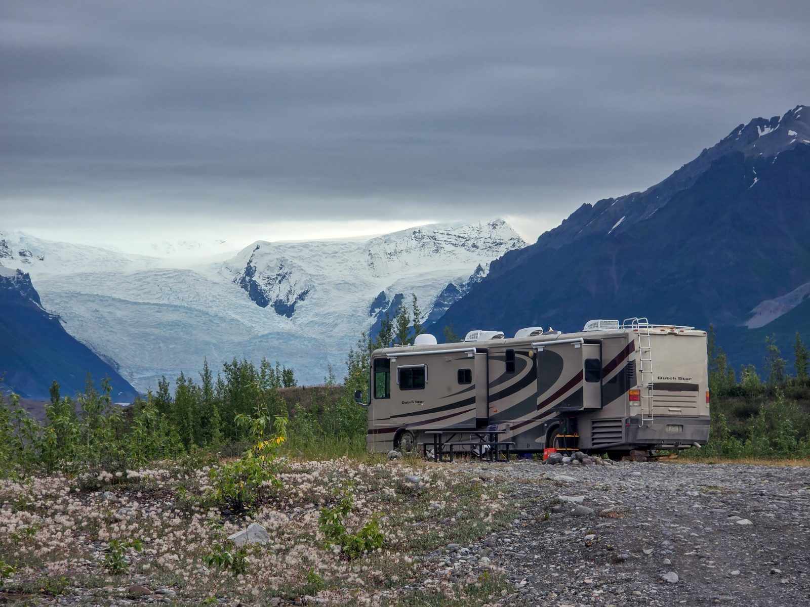 Camper van parked below a glacier and mountain ridge in Alaska
